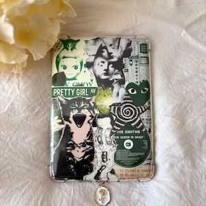 Könnte beinhalten: Transparente Handyhülle mit einem Collage-Design mit einer schwarz-weißen Katze, Gesichtern und dem Text "PRETTY GIRL AV". Ein kleiner Anhänger mit einer weißen und goldenen Blume hängt unten. Die Hülle hat verschiedene grüne und weiße Elemente.