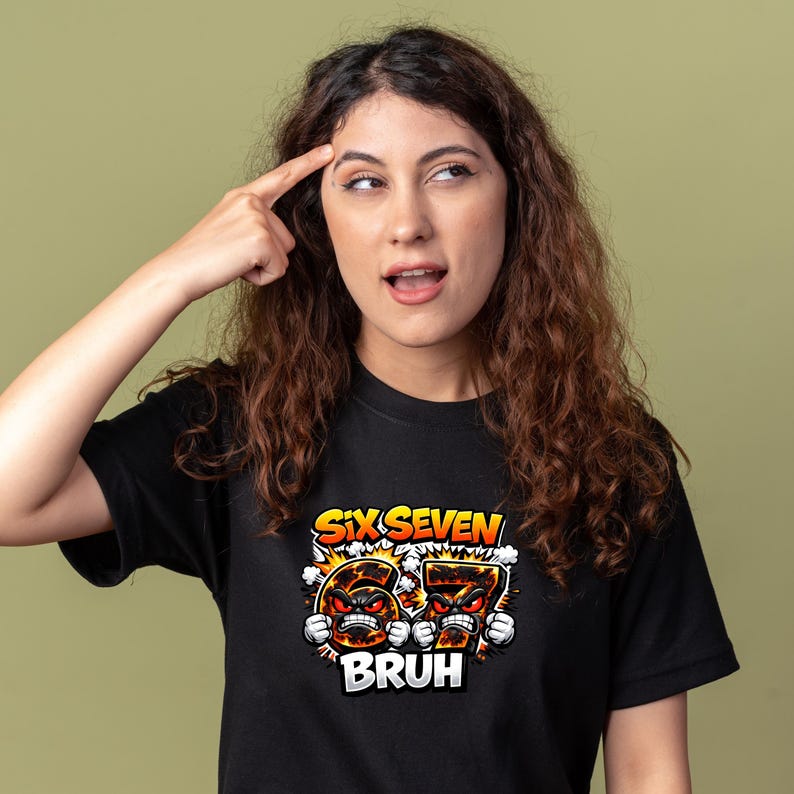 May include: Black t-shirt with the text "SIX SEVEN BRUH" in orange and white. The graphic features cartoon-style numbers with angry faces. The person in the image is pointing to their head.