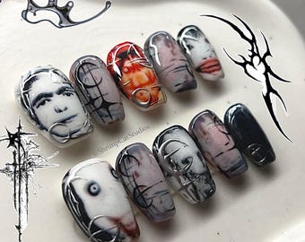 May include: A set of ten press-on nails in a small coffin shape, featuring a mix of black, white, and red designs. The nails display various graphic prints including human faces, abstract line art, and textured patterns with silver accents.