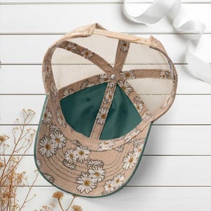 Light pink women’s Christian trucker hat with white embroidered “Jesus Saves” text, two toned hat. Styled on a smiling woman with curly ponytail in front of a modern church. Vintage washed unstructured ponytail baseball cap with feminine floral details and faith-inspired boutique style.