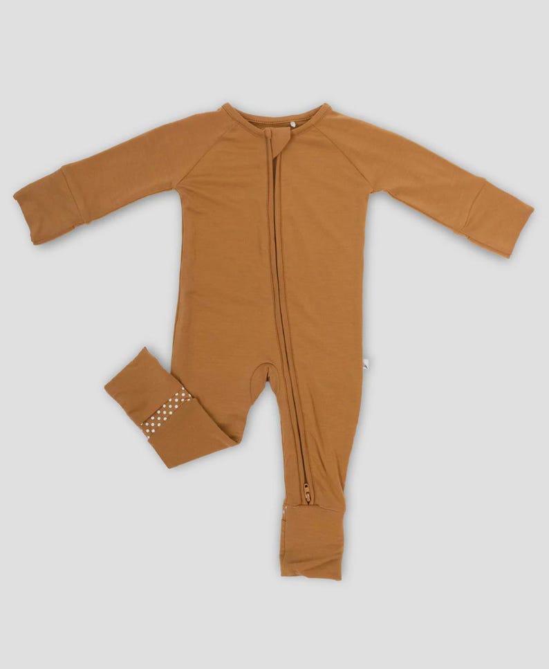 K&ouml;nnte beinhalten: Ein brauner Baby-Schlafanzug mit langen &Auml;rmeln und einem durchgehenden Rei&szlig;verschluss. Der Schlafanzug hat ein kleines gepunktetes Muster an den Kn&ouml;chelb&uuml;ndchen. Dieses bequeme Kleidungsst&uuml;ck ist f&uuml;r Babys konzipiert.
