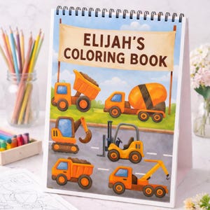 May include: A spiral-bound coloring book titled "ELIJAH'S COLORING BOOK" featuring illustrations of orange construction vehicles. The cover shows a dump truck, cement mixer, excavator, forklift, and tow truck on a road.