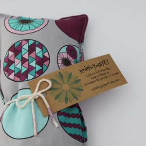 May include: A gray and teal patterned hot or cold rice bag with a brown tag that reads "made for youByKT Cold or Hot Rice Bag Keep in freezer or Microwave 50 seconds - 1 minute madeforyoubyKT etsy.com"