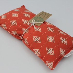 May include: A red and white patterned eye pillow with a small tag that says "Made with Love".