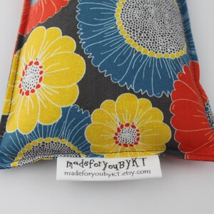 May include: A triangular-shaped fabric item with a floral pattern in yellow, blue, and red on a dark gray background. The item has a white tag with the text "madeforyoubyKT" and "madeforyoubykt.etsy.com".