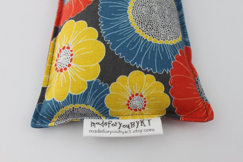 May include: A triangular-shaped fabric item with a floral pattern in yellow, blue, and red on a dark gray background. The item has a white tag with the text "madeforyoubyKT" and "madeforyoubykt.etsy.com".