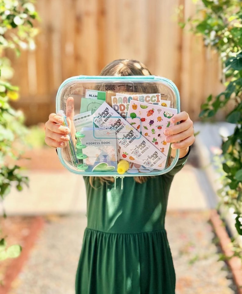 May include: A clear rectangular zippered pouch containing stationery items including a small address book, sticker sheets with alphabet letters and vegetable illustrations, and several cards with the text Happy Mail Has Arrived printed on them.