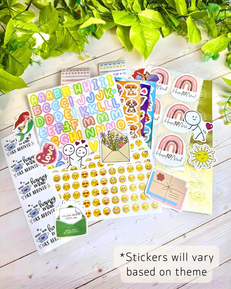 May include: A collection of assorted decorative stickers featuring colorful alphabet letters, emojis, rainbows with the text Happy Mail, cartoon dogs, stick figures, floral envelopes, and suns. A rectangular note states Stickers will vary based on theme.