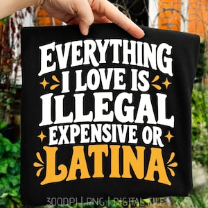 May include: A black t-shirt featuring bold white and yellow text that reads Everything I Love Is Illegal Expensive Or Latina. The design includes decorative star and flourish accents surrounding the lettering, printed on a dark fabric background.
