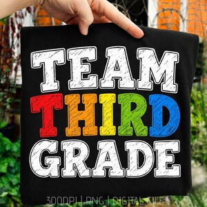 Könnte beinhalten: Ein schwarzes T-Shirt mit dem weißen Text TEAM oben, dem mehrfarbigen Text THIRD GRADE in der Mitte mit roten, orangen, gelben, grünen und blauen Buchstaben und dem weißen Text GRADE unten, inklusive 300DPI PNG DIGITAL FILE Text.