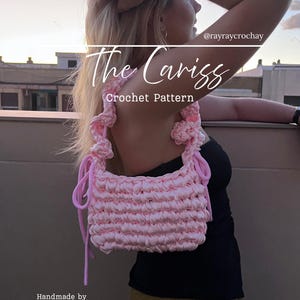 May include: A light pink crochet handbag featuring a rectangular body with a textured, ribbed stitch pattern and a gathered handle with side drawstring ties. The image includes the text The Cariss Crochet Pattern, @rayraycrochay, and Handmade by Rayray.