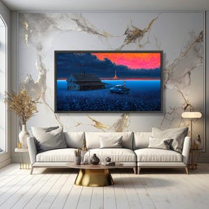 Puede incluir: Una impresión artística enmarcada que representa una escena rural con una casa, una camioneta y un lanzamiento de cohete contra un atardecer vibrante. La obra de arte presenta una paleta de colores azul y naranja, creando una atmósfera dramática y surrealista. La impresión se exhibe sobre un sofá blanco.