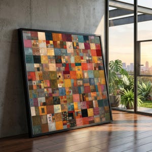 May include: A framed abstract art piece featuring a patchwork design of various colorful squares. The artwork is predominantly red, blue, yellow, and green, with a black frame. The piece is leaning against a concrete wall near a window.