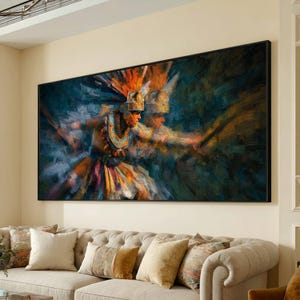 May include: Large framed artwork depicting a figure in traditional attire, possibly a dancer or warrior, with a feathered headdress and ornate clothing. The painting uses a palette of blues, oranges, and yellows, with visible brushstrokes. The artwork is displayed above a beige sofa.