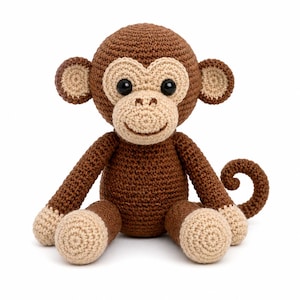 May include: A crocheted monkey stuffed animal featuring dark brown yarn for the body, head, arms, and legs, with light beige yarn accents on the face, ears, hands, and feet. The monkey has two black plastic eyes and a stitched brown mouth.