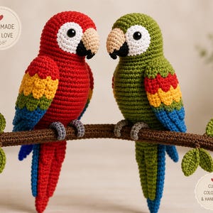 Puede incluir: Dos loros de ganchillo hechos a mano posados en una rama marrón. Uno es rojo con detalles amarillos, azules y verdes. El otro es verde con detalles coloridos similares. Las aves tienen picos negros y ojos blancos. El texto "Handmade with Love" y "Cute Colorful & Handmade" está incluido.