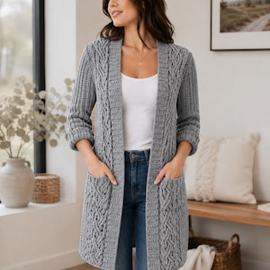 May include: A gray, long-sleeved cardigan with a cable knit design and two front pockets. The open-front sweater is knee-length and worn over a white top and blue jeans. The cardigan is a comfortable, stylish garment.