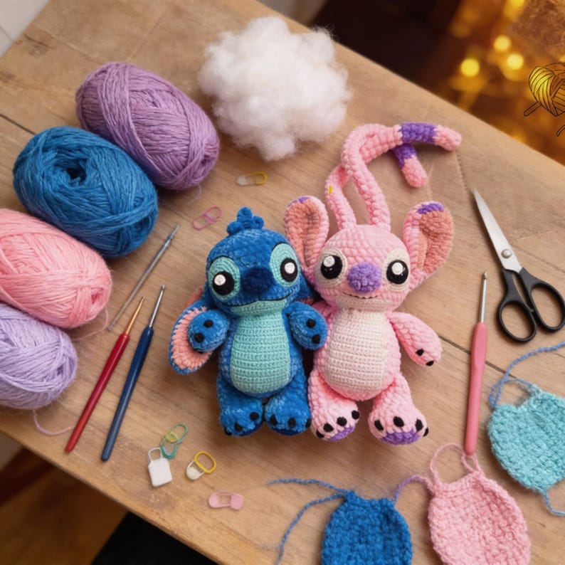 May include: Two crocheted plush toys, one blue and one pink, sit on a wooden surface. The blue toy has large black eyes and a turquoise belly. The pink toy has long ears and a purple nose. Yarn, crochet hooks, and other crafting supplies surround the toys.
