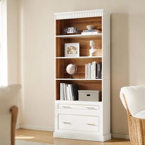 May include: A tall, white wooden bookcase with multiple shelves and two drawers. The shelves display books, decorative items, and a globe. The interior of the bookcase is a warm wood tone, contrasting with the white exterior. Gold-toned hardware accents the drawers.