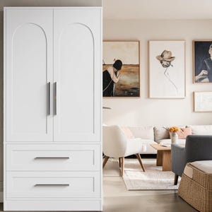 May include: A tall white wardrobe featuring two doors with arched top panels and two lower drawers. The unit includes vertical silver-toned metal handles on the doors and horizontal silver-toned metal pulls on each of the two drawers.