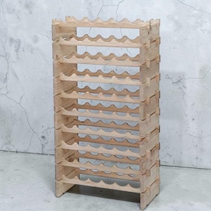 May include: A natural wood wine rack with a capacity for multiple bottles. The rack is constructed from light-colored wood and features a wave-like design to cradle each bottle. The design is a freestanding, vertical structure.