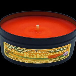 A round, black candle tin with an orange-colored wax and a white wick. The label reads "Sandalwood Rose" and "Hand Poured Premium Scented Para-Soy Candle". The candle weighs 6 oz (170g).