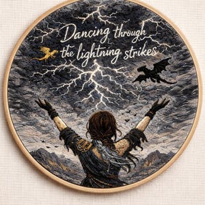 May include: Embroidered artwork in a wooden hoop shows a woman with arms raised towards a stormy sky with lightning. Two dragons and the text "Dancing through the lightning strikes" are also featured.
