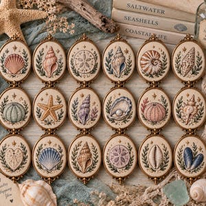 Puede incluir: Una colección de dieciocho parches bordados de forma ovalada, cada uno con una ilustración única de conchas o vida marina enmarcada en bronce antiguo, dispuestos en tres filas sobre una superficie de madera clara con elementos costeros.