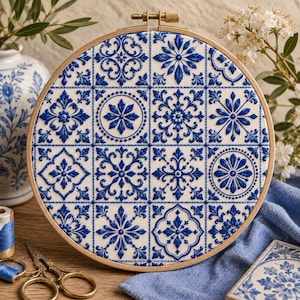 May include: A round embroidery hoop featuring a blue and white tile design. The design is composed of various floral and geometric patterns. The wooden hoop holds the fabric taut, showcasing the detailed needlework. The color palette is a classic blue and white.