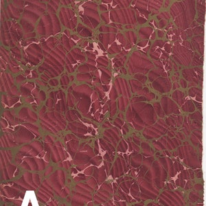 May include: A red and gold marbled paper with a letter A in the bottom left corner.
