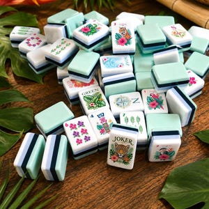 May include: A set of rectangular Mahjong tiles featuring light green backs and white faces with colorful illustrations of tigers, leopards, parrots, tropical flowers, compasses, and text including Joker, Green, Red, and Soap in various fonts.