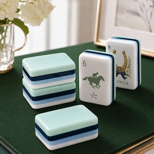 May include: A set of rectangular mahjong tiles featuring a layered color scheme of mint green, navy blue, and light blue. One tile displays a jockey on a horse with the number 6 and a Chinese character, while another shows a horseshoe and the number 8.