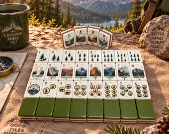 Puede incluir: Un juego de fichas de mahjong con temática de parques nacionales dispuestas sobre una alfombrilla de tela texturizada. Las fichas presentan ilustraciones de árboles, montañas y vida silvestre, con etiquetas numeradas y dorsos verdes.
