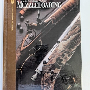 May include: A hardcover book titled "The Complete Hunter Muzzleloading" with a brown spine. The cover features a detailed image of a muzzleloading rifle, with bullets and other hunting equipment. The book is part of "The Hunting & Fishing Library".