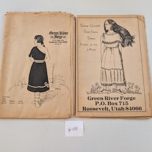 May include: Two vintage sewing pattern covers from Green River Forge. One features a side-seam dress illustration, the other a Native American-style dress. Both covers have black and white illustrations and text, including the address in Roosevelt, Utah.
