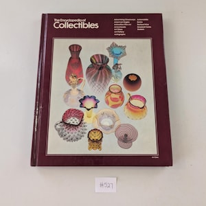 May include: A maroon-covered book titled "The Encyclopedia of Collectibles". The cover displays a collage of colourful glass collectibles. The book's spine is also maroon.