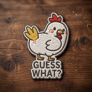 May include: Embroidered patch featuring a cartoon chicken with a red comb, yellow tail, and the text "GUESS WHAT?". The patch has a white body, brown outline, and is set against a wooden background.