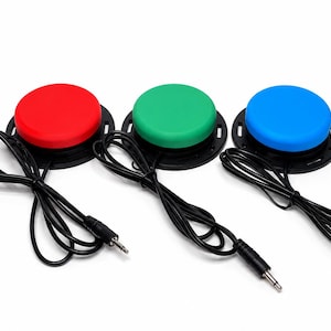 May include: Three circular push buttons in red, green, and blue, each mounted on a black circular base. Each button features a black cord extending from the side, terminating in a standard 3.5mm audio jack connector for external device connectivity.