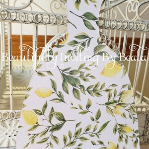 Puede incluir: Recorte decorativo de papel con forma de vestido, con fondo blanco y un estampado de limones amarillos y hojas verdes. El texto "Beautifully Inviting By Beata" es visible.