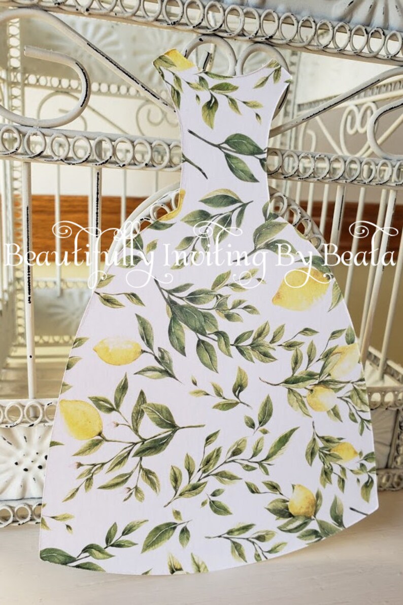 Puede incluir: Recorte decorativo de papel con forma de vestido, con fondo blanco y un estampado de limones amarillos y hojas verdes. El texto "Beautifully Inviting By Beata" es visible.