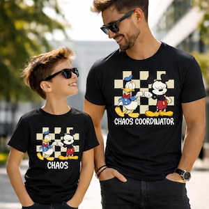 May include: Two black t-shirts with a cartoon graphic of Donald Duck and Mickey Mouse on a checkered background. The shirt on the right says "Chaos Coordinator", and the shirt on the left says "Chaos".