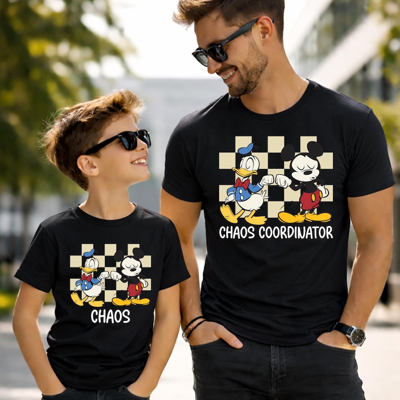 May include: Two black t-shirts with a cartoon graphic of Donald Duck and Mickey Mouse on a checkered background. The shirt on the right says "Chaos Coordinator", and the shirt on the left says "Chaos".