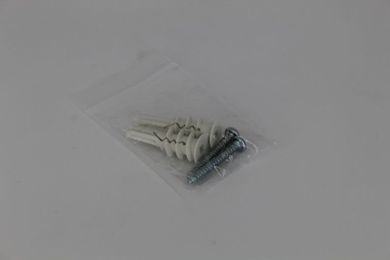 May include: A clear plastic bag containing several white wall anchors and two silver screws. The anchors have a unique design with a central opening and a ribbed exterior. The screws are metal with a spiral design.