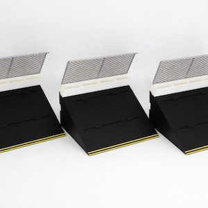 May include: Three black display stands with a white top section and a silver mesh cover. Each stand has a yellow stripe along the bottom edge. The stands are angled, creating a tiered display.