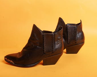 Peut inclure: Une paire de bottines en cuir noir à bout pointu et talon bloc. Les bottines ont un détail de couture décorative à l'arrière du talon.