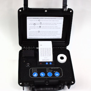 May include: A black, open case with a built-in printer and a roll of white paper. The case has a control panel with buttons and a small screen. The text "Model ADL-1 OTPF Operating Instructions" is visible on the inside of the case.