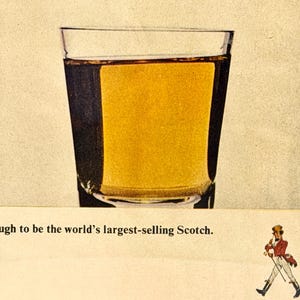 May include: A clear glass filled with amber liquid, likely a spirit, is the focal point. The image is an advertisement, with the text "...to be the world's largest-selling Scotch." A small illustration of a man in a red coat and black boots is also present.