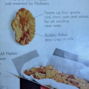 May include: An advertisement for TEAM Flakes cereal by Nabisco. The image shows a close-up of a single, bubbly flake and a box filled with flakes. Text highlights the cereal's ingredients: rice, corn, oats, and wheat.