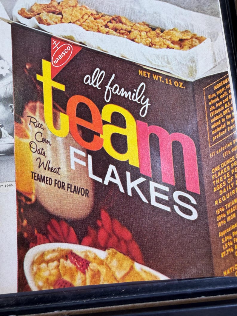 May include: Vintage box of Nabisco Team Flakes cereal. The box is brown with the words "team flakes" in large yellow, orange, and pink letters. The box also includes the words "all family" and the ingredients.
