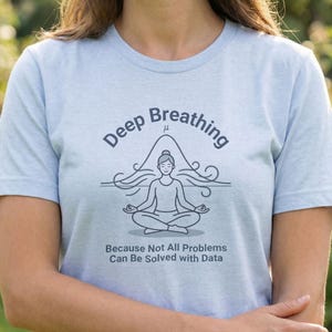 May include: Pale blue t-shirt featuring the words "Deep Breathing" and a line drawing of a meditating person. The text below reads "Because Not All Problems Can Be Solved with Data."